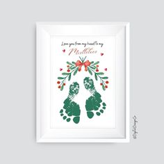 a christmas card with two baby feet and holly wreaths on the bottom, in green