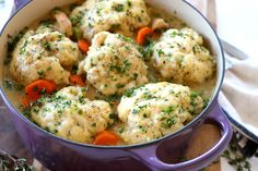 a pot filled with dumplings and carrots on top of a wooden cutting board