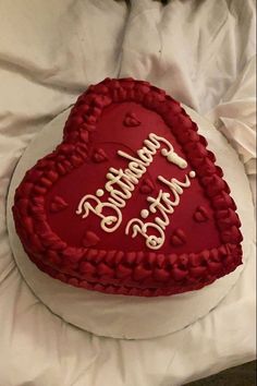 a heart - shaped cake with writing on it is sitting on a white sheet covered bed