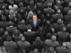 a man in a suit and tie surrounded by many other people, looking up at the camera