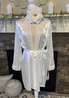 This luxurious short robe is designed to make you feel exquisite, whether you're lounging in elegance or preparing for a special evening. Its combination of sumptuous fabric, detailed craftsmanship, and romantic design elements creates a garment that is both breathtaking and unforgettable. More details about this piece.  Tag has price tag with $68 with color as "Ivory" but it's more of a white as listed.  Attached Tie Sash  Chiffon trim on sleeves  Floral Pearl and clear sequins appliqué on each Fitted Satin Robe For Loungewear, Elegant Long Sleeve Sleepwear For Wedding Night, Feminine Satin Robe For Loungewear, Elegant Satin Finish Robe For Loungewear, Fitted Satin Robe For Wedding Night, Elegant Fitted Open Front Kimono, Elegant Open Front Kimono For Wedding, Fitted Satin Robe With Lace Trim, Elegant Satin Robe For Loungewear