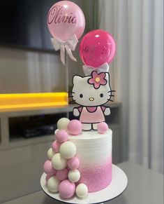 a hello kitty birthday cake with balloons on the top and one balloon in the air