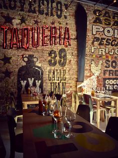 a restaurant with brick walls and neon signs on the wall, along with empty wine glasses