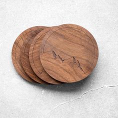 three wooden coasters with mountains engraved on them