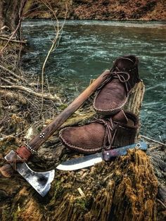 an old pair of boots sitting on top of a tree stump next to a river