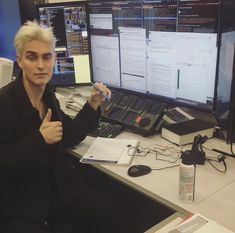 a man sitting at a desk in front of two computer monitors giving the thumbs up