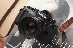 a camera sitting on top of a book next to a wooden box with a leather strap