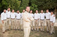 a man standing in front of a group of men wearing tan pants and white shirts