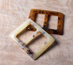 two square shaped objects sitting on top of a wooden table next to each other with holes in them