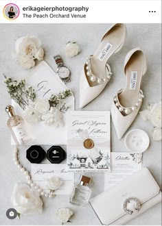 the wedding stationery is laid out with white flowers and pearls on top of it