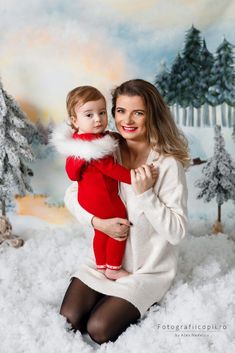 a woman holding a baby in her arms while posing for a photo with snow on the ground