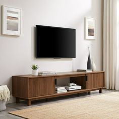 a flat screen tv sitting on top of a wooden entertainment center next to a window