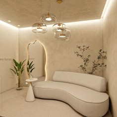 a white couch sitting in a room next to a mirror and vase with flowers on it