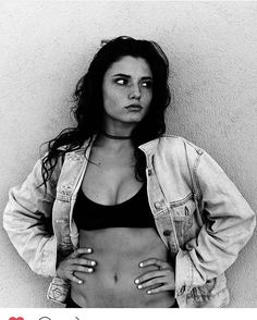 a black and white photo of a woman with her hands on her hips, wearing a jean jacket