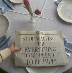 a newspaper sitting on top of a table next to a vase with tulips