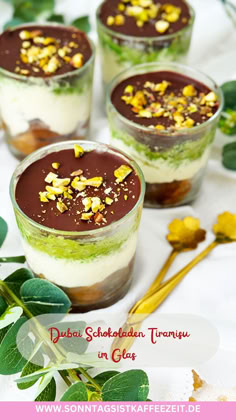 three desserts with chocolate and nuts in them on a white tablecloth next to flowers