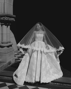 a woman in a wedding dress and veil standing on a checkered floor with columns behind her