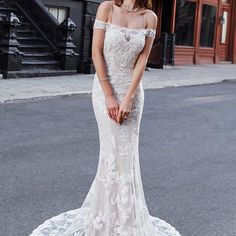 a woman in a wedding dress standing on the street with her hand on her hip