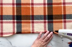 someone is using a sewing machine to sew the fabric on a plaid pillow cover