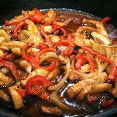 a skillet filled with chicken, peppers and onions