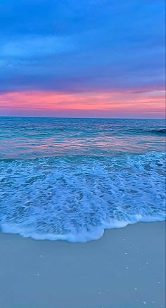 the ocean waves are coming in to shore at sunset or dawn with pink and blue colors