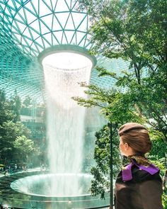 air hostess standing in front of the rain vortex at the jewel in Singapore Changi Airport