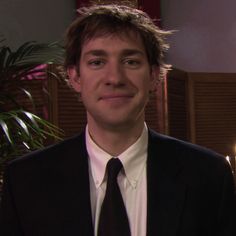 a young man in a suit and tie looking at the camera with a smile on his face