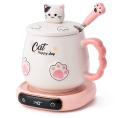 a white cat mug with pink handles and feet sitting on top of it's holder