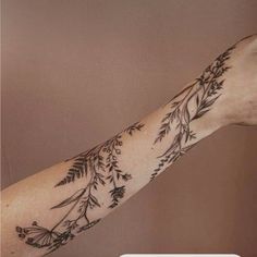 a woman's arm with flowers and leaves on it