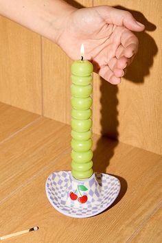 a person holding a lit candle on top of a wooden table next to two matches