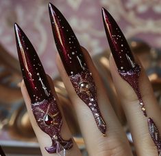 a woman's hand with red and gold stiled nail designs on it,