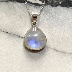 This beautiful Moonstone Pendant is set in Sterling Silver, stamped 925.  The moonstone is around 25x22mm in size suspended on a silver chain which adjusts from 16-18inches, perfect for any necklines. The Rainbow Moonstone has a beautiful blue flash which appears as the light catches it.  Each piece of Jocale Jewellery comes in a beautiful box making it the ideal gift! Natural Rainbow Moonstone, Real Moonstone, Moonstone Necklace, Blue Pendant, Stylish Jewellery, Affordable Jewellery, Moonstone Jewelry, Moonstone Jewellery, Blue Jewelry, White Jewellery, Blue Flash, June Birthstone  **Note From Our Gemmologist- Marie Chalmers ** Moonstone is a beautiful gemstone which shows a flash of blue as the stone moves called a schiller. This will happen in two orientations so our moonstone has been Silver Teardrop Gemstone Crystal Necklace, Teardrop Cabochon Necklace For Anniversary, Anniversary Teardrop Cabochon Necklace, Anniversary Cabochon Teardrop Necklace, Celestial Moonstone Jewelry With Natural Stones, Celestial Jewelry With Oval Natural Stones, Celestial Oval Jewelry With Natural Stones, Silver Birthstone Teardrop Pendant Crystal Necklace, Sterling Silver Teardrop Gemstone Crystal Necklace