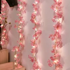 some pink flowers are hanging on a wall with lights in the shape of orchids