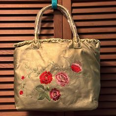 Floral Metallic Tote Bag. Pink, Red And Green Floral Embroidery On One Side. 2 Short Handle Straps. Large Tote Section. 2 Zippered Pockets And One Phone Pocket. Edge Trimmed With Leather Like Twine And Eyelets. Snap Closure. Never Used. Traditional Gold Shoulder Bag For Travel, Red Embroidered Shopping Bags, Gold Tote Gift Bag, Red Embroidered Bags For Shopping, Gold Embroidered Tote Bag, Gold Rectangular Shoulder Bag With Gold Embroidery, Gold Embroidered Shoulder Bag, Avon Bags, Large Tote