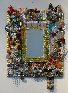 a mirror that is covered in lots of beads and other assorted things hanging on the wall