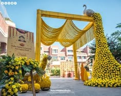 the entrance to an event decorated with yellow flowers and peacocks in front of it