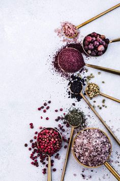 spoons filled with different types of spices on top of a white countertop next to each other