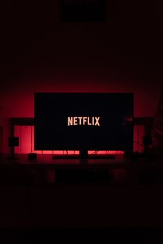 a television screen with the netflix logo lit up on it's side in a dark room