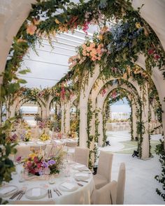 an outdoor dining area decorated with flowers and greenery