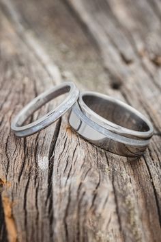 two wedding rings sitting on top of a piece of wood