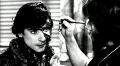 a man is getting his hair cut by another man in black and white, while he looks at the woman's face