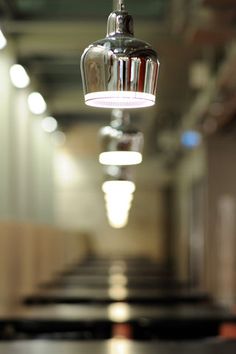 a light hanging from the ceiling in a room with long tables and chairs behind it