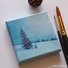 a christmas tree painted on a canvas next to some paintbrushes and a pine cone