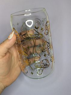 a hand holding up a glass with writing on the bottom and gold trimmings