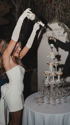 a man and woman standing next to each other in front of a table with wine glasses on it