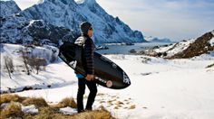 a man holding a surfboard while standing in the snow