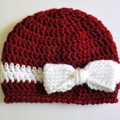 a crocheted hat with a white bow on the side and a red knitted beanie