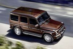 a brown mercedes g class driving down the road