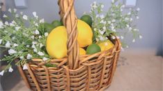 a wicker basket filled with lemons, limes and white flowers on a table