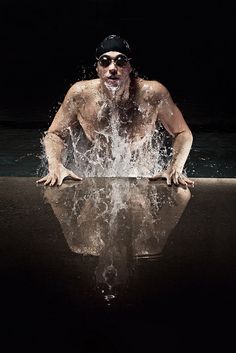 a shirtless man splashing water on his face